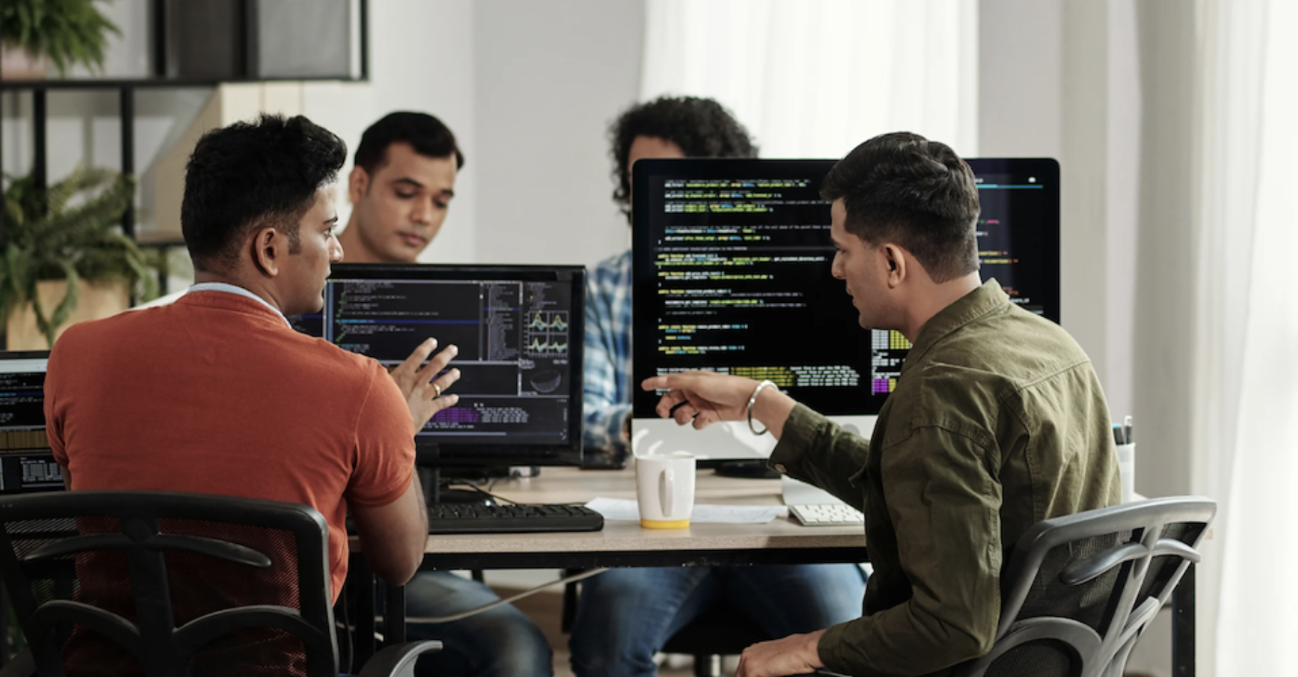 Coders sitting and talking at computers